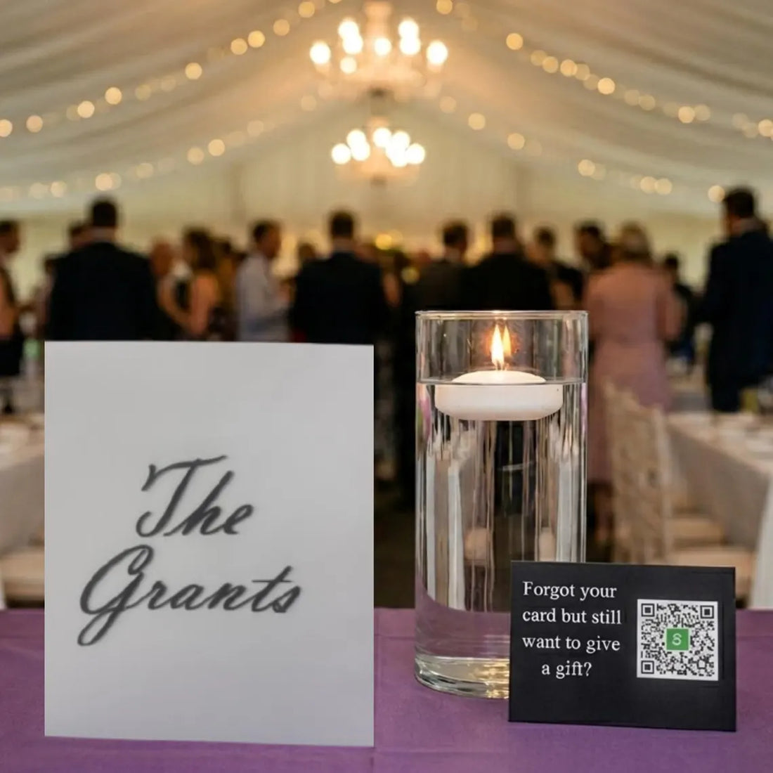 A small black rectangular card with white text reading 'Forgot your card but still want to give a gift?' next to a QR code containing a green square with an S, placed on a purple surface.